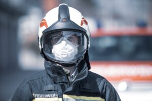 Feuerwehrmann in Schutzausrüstung vor Feuerwehrfahrzeug