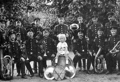 Kind und Blaskapelle posieren für ein Gruppenfoto.