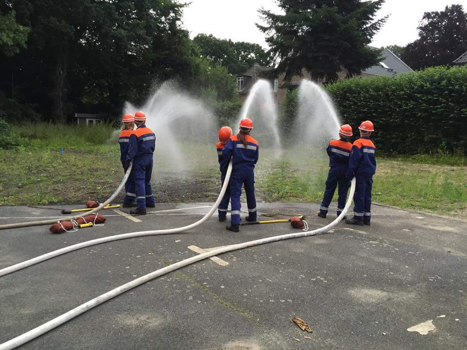 Jugendfeuerwehr übt mit Schläuchen im Freien.